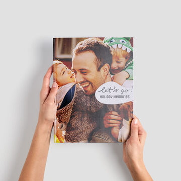 Een persoon houdt een CEWE fotoboek met vakantiefoto's vast.