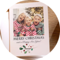 Twee kinderen in feestelijke kerstkleding lachen voor een versierde boom.