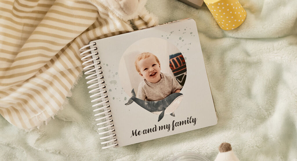 Un album CEWE intitulé 'Me and my family', décoré avec un motif de baleine, posé sur un fond doux.