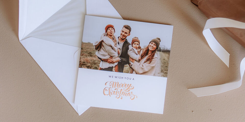 Famille en vêtements chauds souhaitant joyeux Noël avec un message sur une carte.