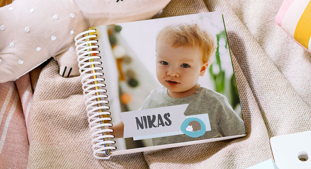 Un album photo CEWE sur une couverture avec des jouets autour. Il porte le nom 'Niklas' sur la couverture.
