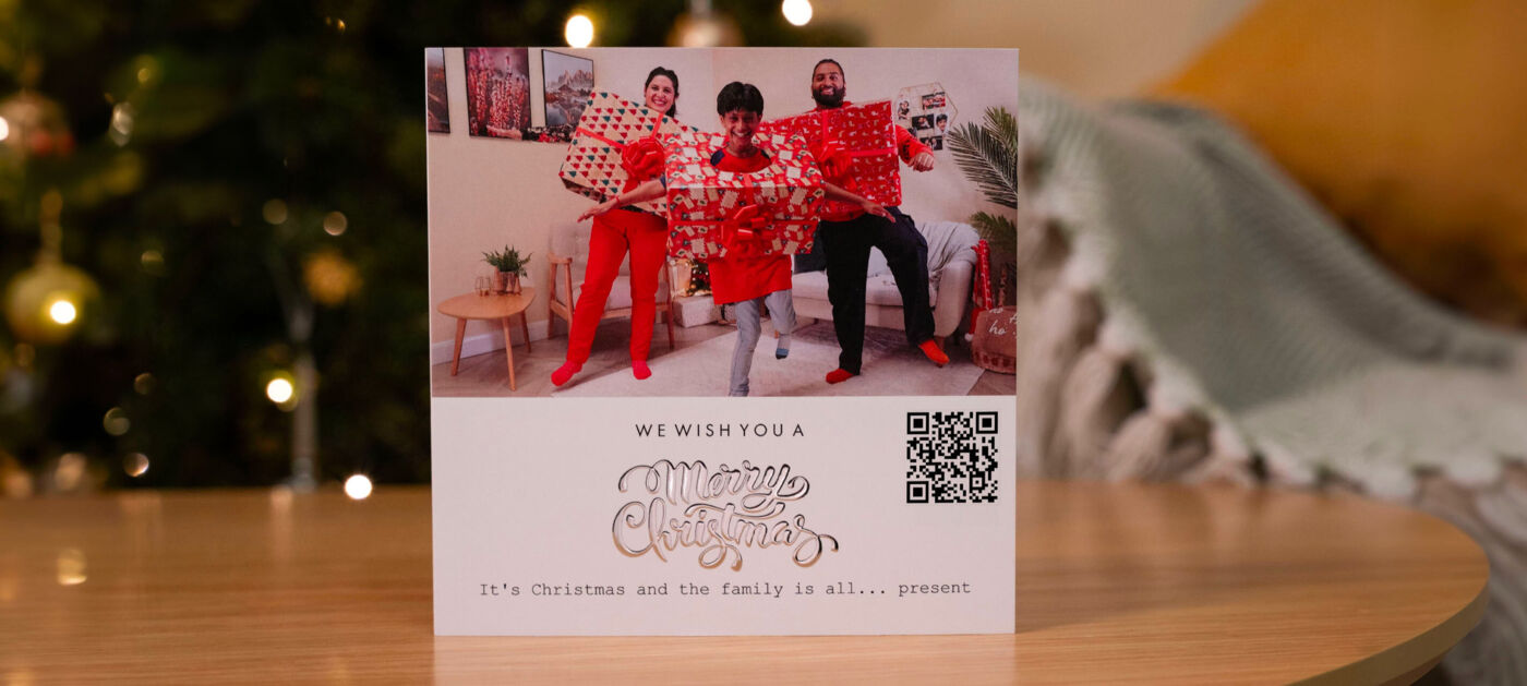 Trois personnes joyeuses en tenues rouges avec des cadeaux et un message de Noël