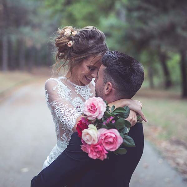 Un couple heureux s'enlace dans la nature tandis que la mariée tient des roses