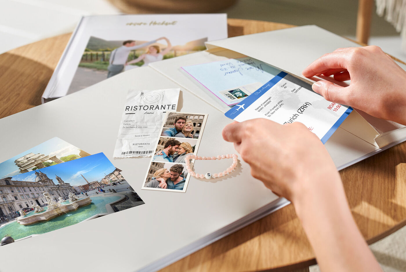 Une personne crée un livre photo avec des souvenirs, y compris des photos de voyages et un collier.
