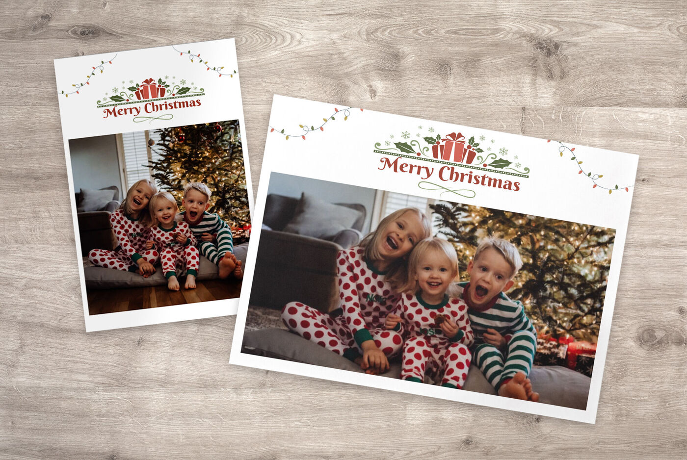 Twee feestelijk geklede kinderen met kersthoedje zitten samen op een bank voor een kerstboom.