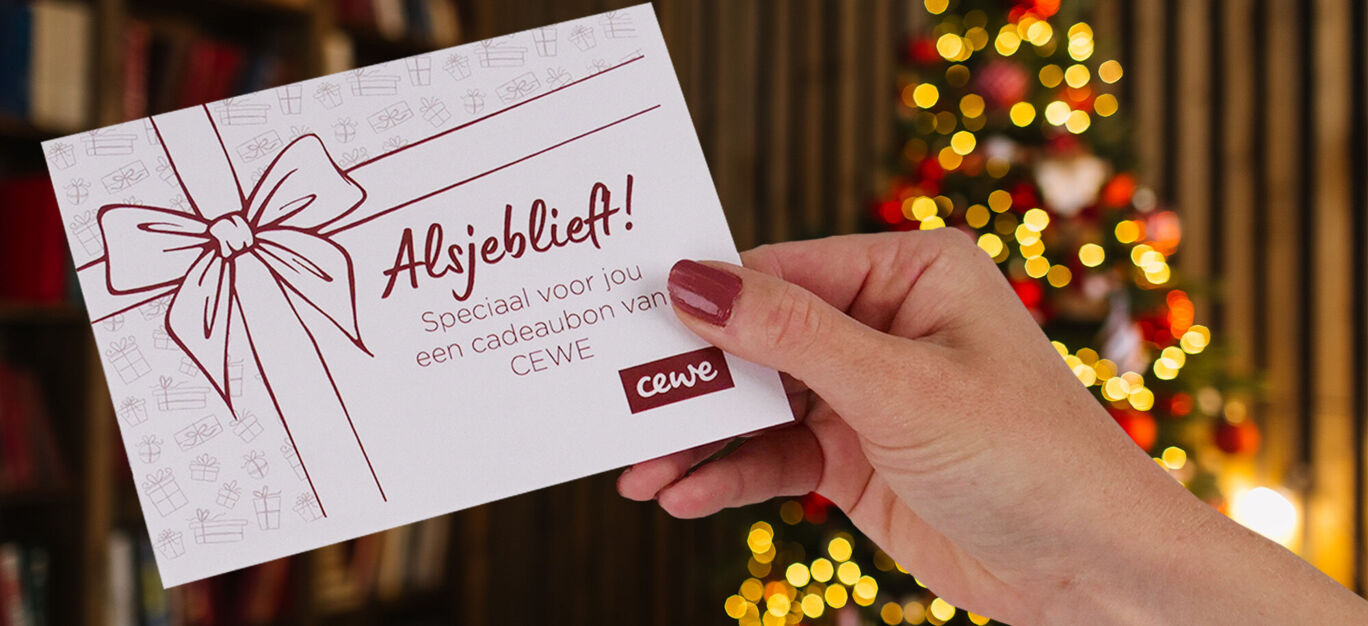Een witte cadeaukaart van CEWE met rode tekst, liggend op een ronde houten tafel. Perfect als cadeau voor een vrouw.